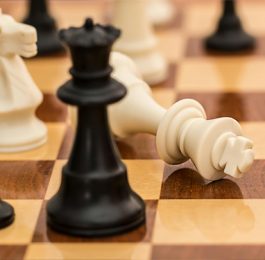 White chess king toppled over on a wooden chessboard