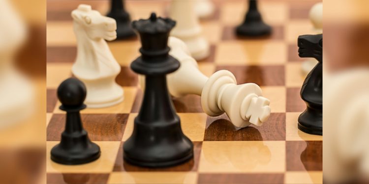 White chess king toppled over on a wooden chessboard