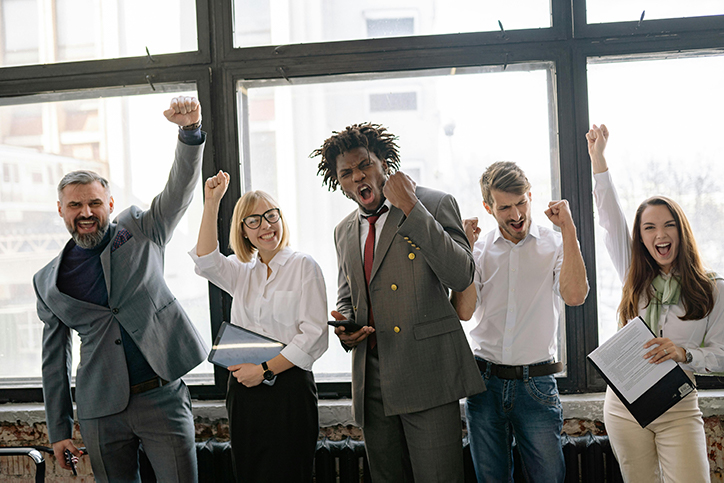 Diverse Team Celebrating Together Group of diverse professionals celebrating with raised arms in a bright workspace