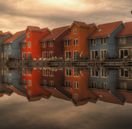 Row of colourful houses perfectly reflected in still water, symbolising reciprocity and mirrored behaviour